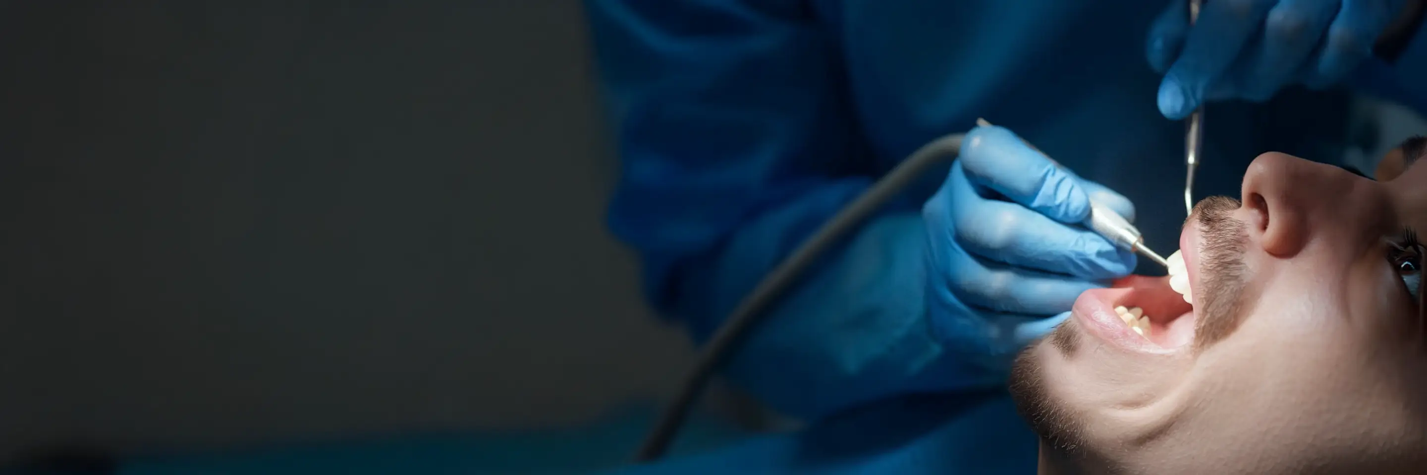 Dentist examines a patient’s teeth with dental instruments.
