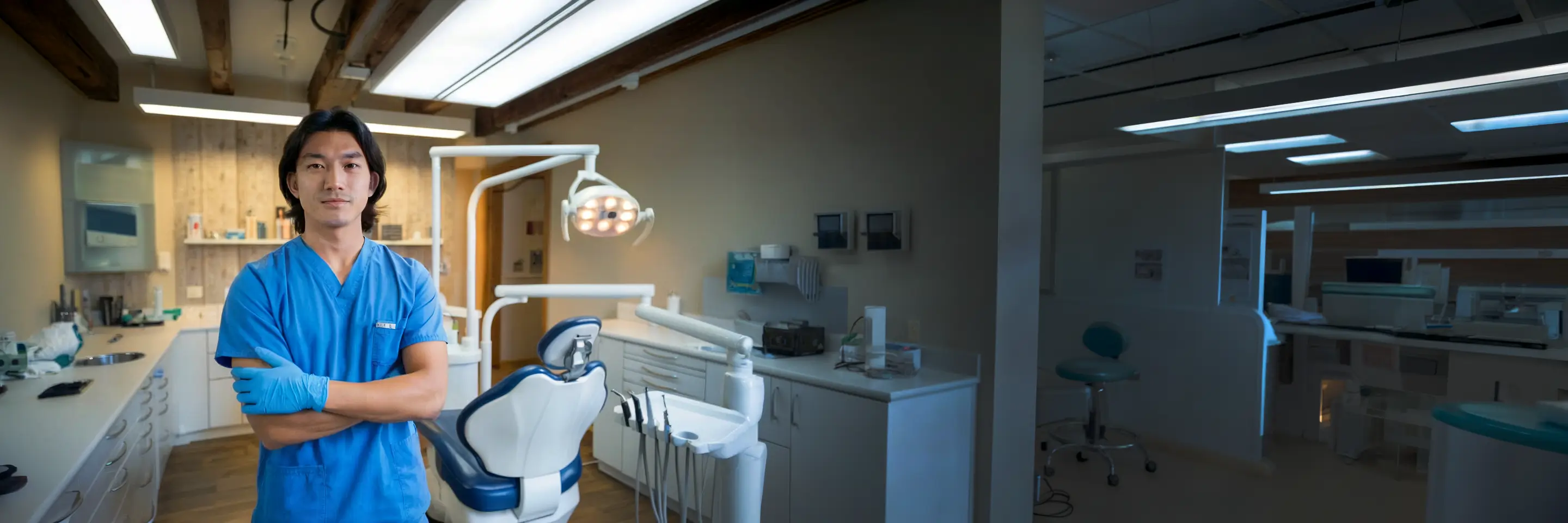 Dental professional standing beside a dental chair in a dental clinic.