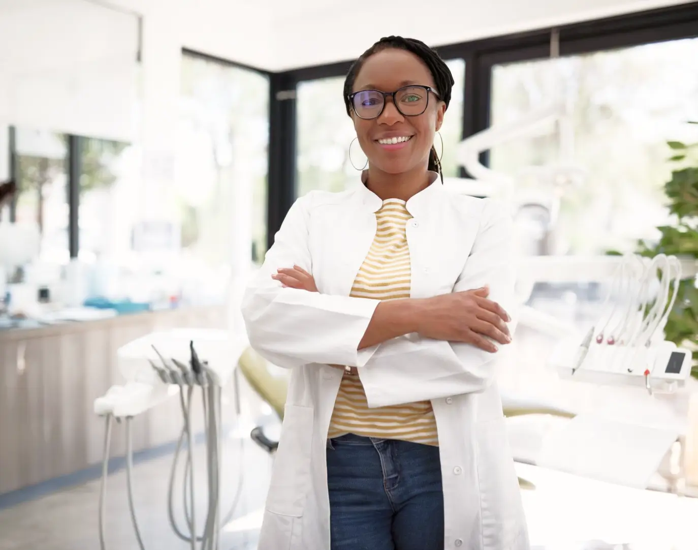Dentist standing in a dental clinic with arms crossed and smiling at the camera