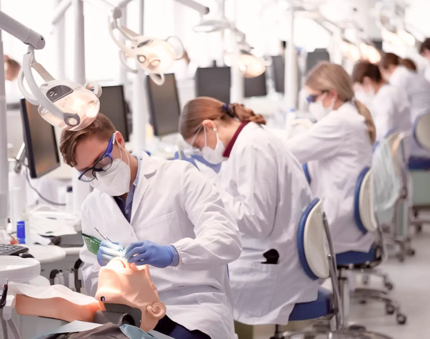 Dental students practicing procedures in a clinical training lab wearing masks and protective eyewear