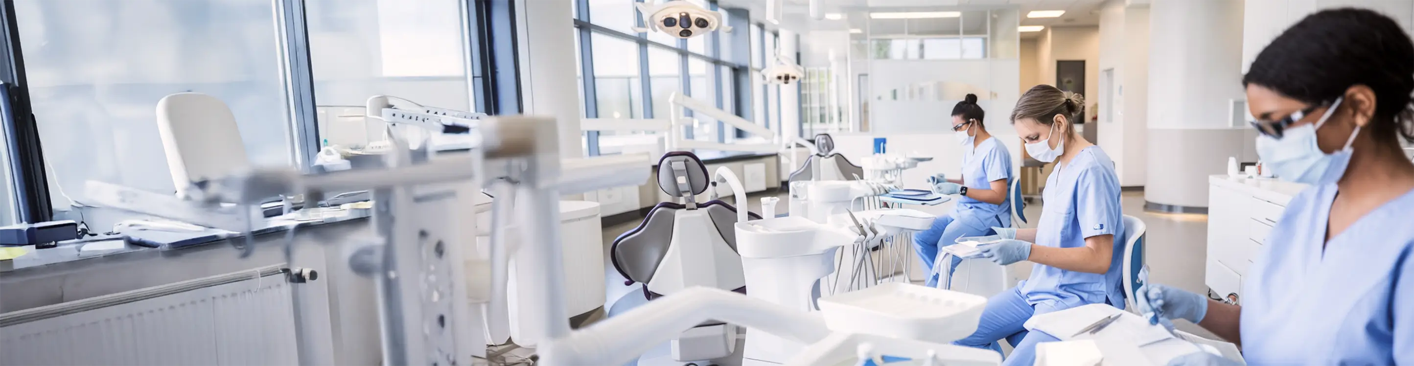 Dental professionals wearing masks and scrubs working in a dental clinic.