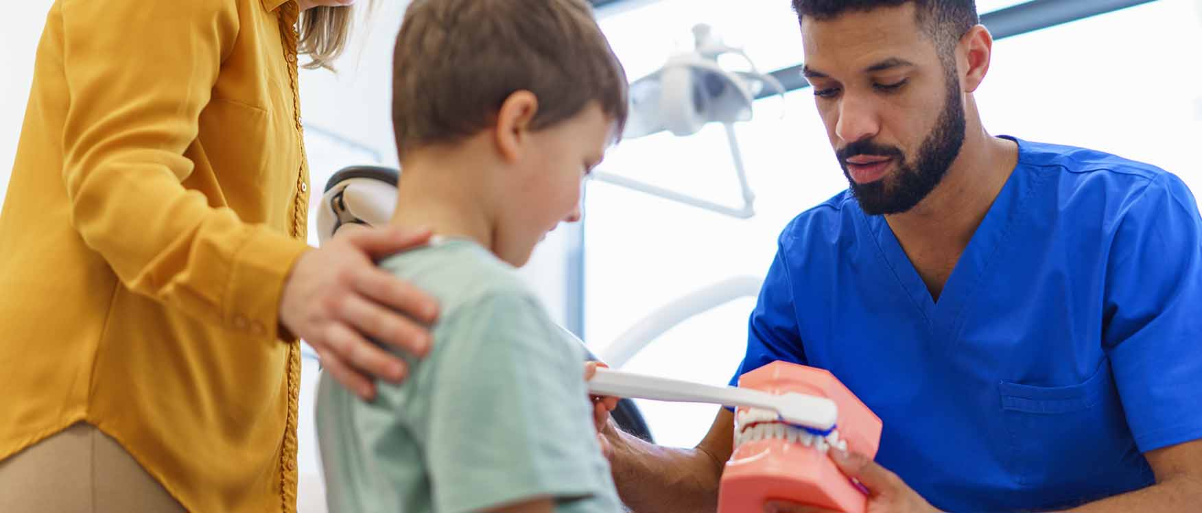 Dentist teaching child how to brush teeth