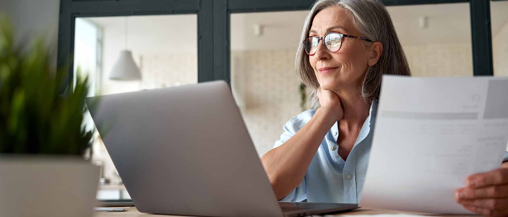 woman at computer holding papers