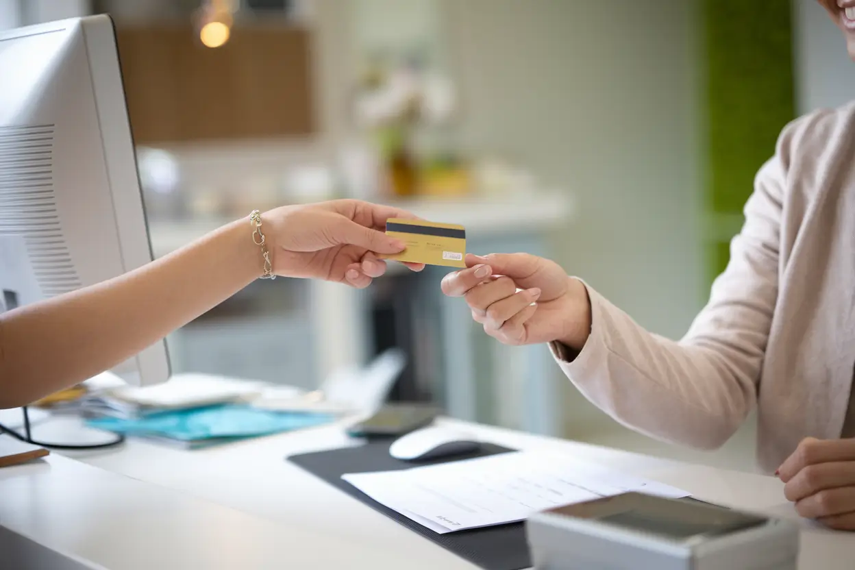 Patient hands a payment card to clinic reception staff.