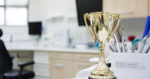 Gold trophy on a counter beside dental instruments in a dental clinic.