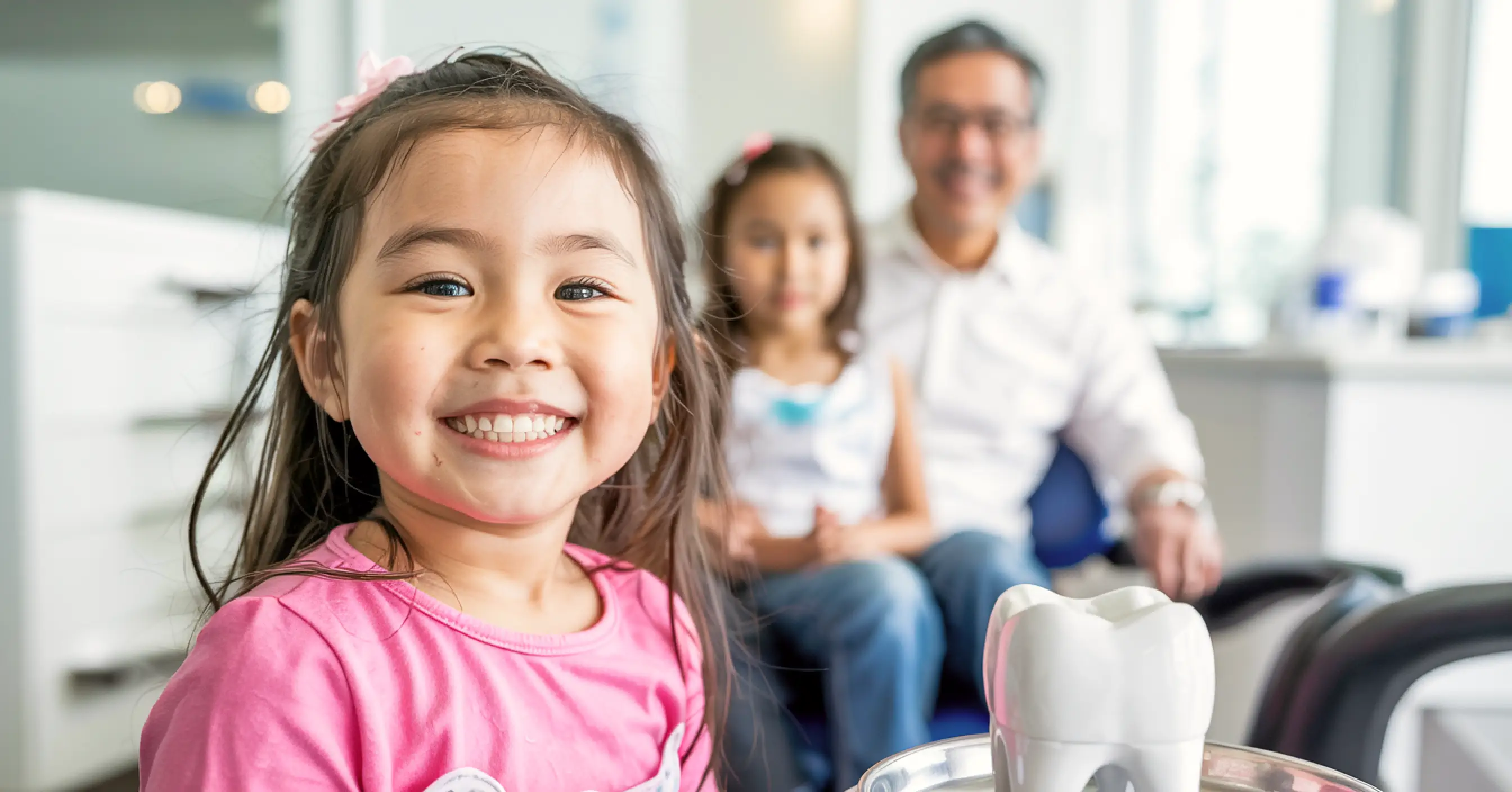 Smiling young girl at a dental clinic with family members in the background