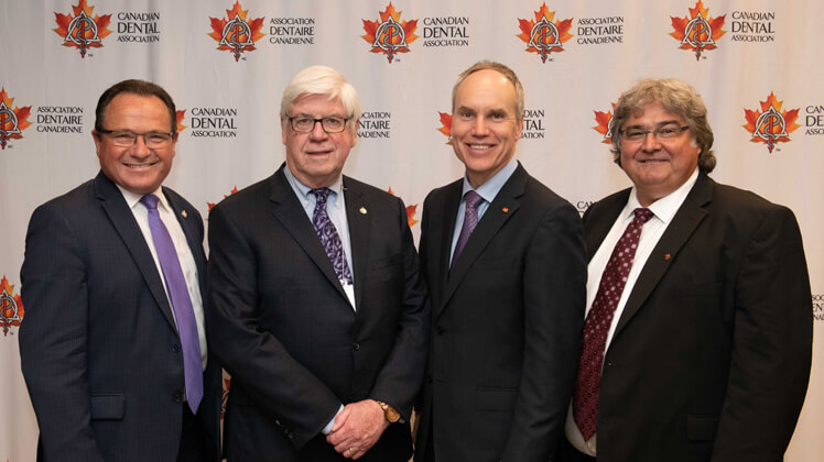 Four men posing at the Canadian Dental Association’s Annual Parliamentary Reception in May 2019, standing in front of a CDA backdrop.